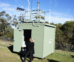 two women outside an air monitoring equipment shed