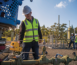 a man in hard hat and hi viz vest inspecting a gas pipeline