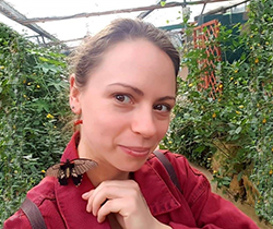 a young woman in a dark red shirt has a butterfly on her collar