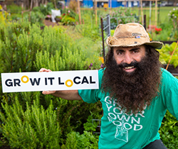 a bearded Costa Georgiadis holding a grow it local sign