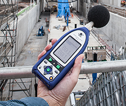 EPA officer with hand-held noise monitor above construction site