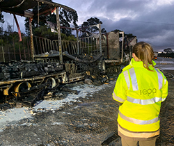 , EPA officer next to burning truck assessing environmental impact