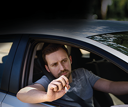 man throwing cigarette butt out of car window 