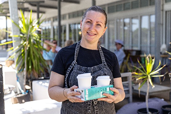 smiling staffer with coffee cups