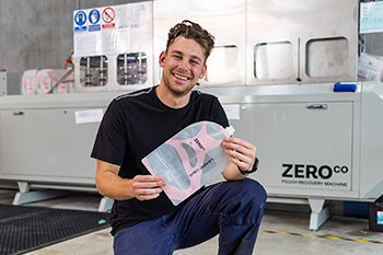 worker holding a fillable pouch in front of the pouch washing machine